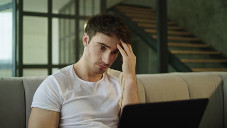 hombre cansado trabajando con una computadora portátil en la oficina de casa. freelancer leyendo noticias en la computadora