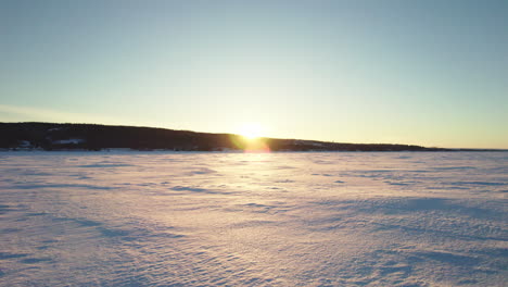 Flying-drone-above-a-frozen-lake-in-canada-at-golden-hour