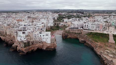 aerial orbit reveal of bay beach near polignano, travel destination town in italy