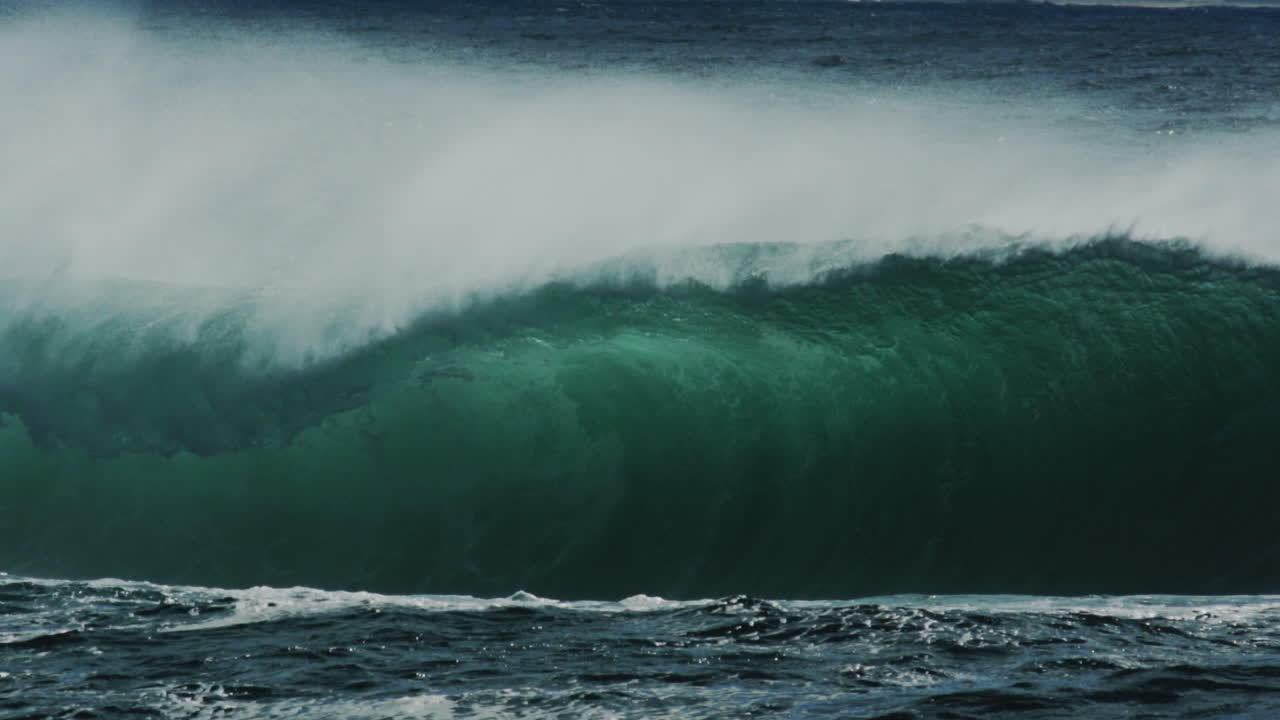 Dark green wave thickens and throws spray wide as it crashes down with heavy power, slow motion