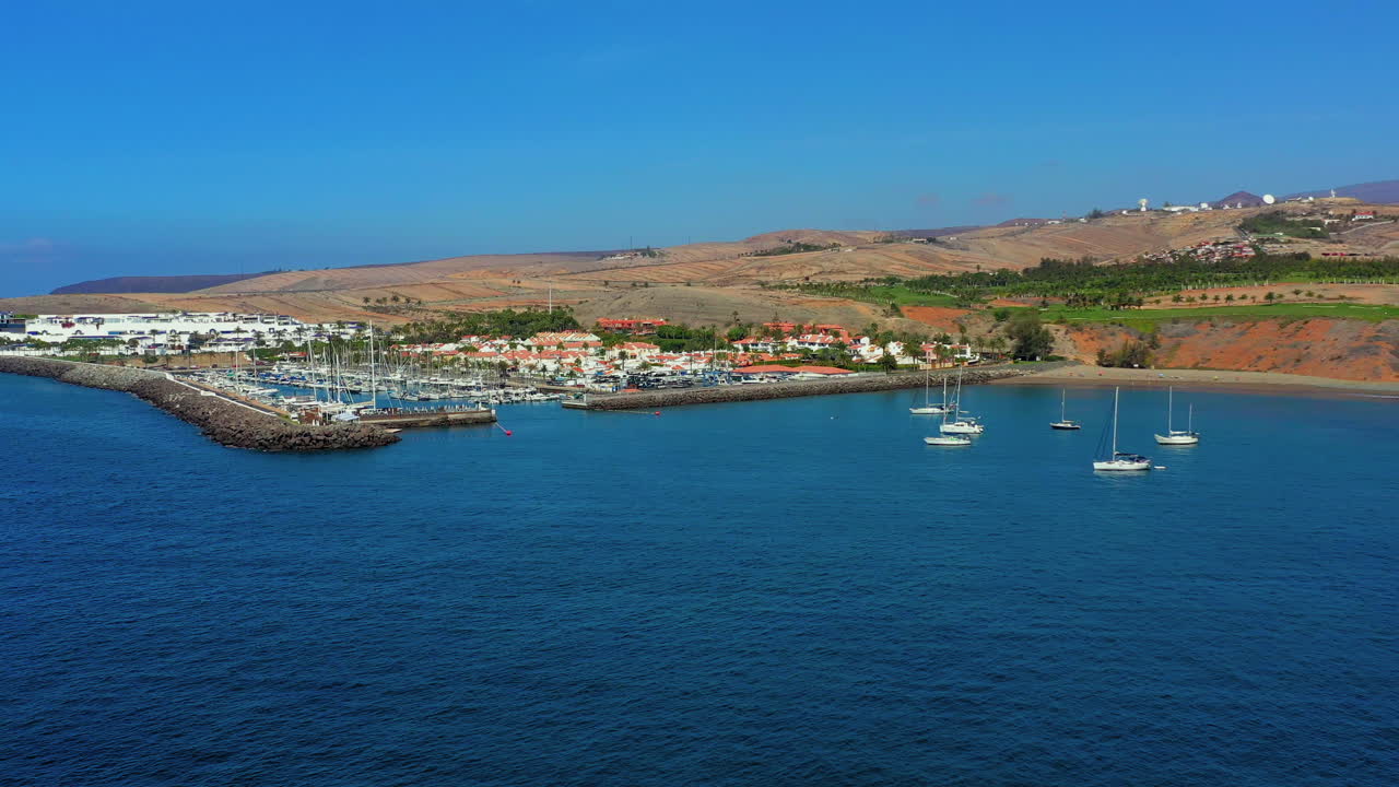 AERIAL: Flying above busy tropical island port filled with boats and ferries. Countless ships sail to and from bustling harbor on exotic beach.