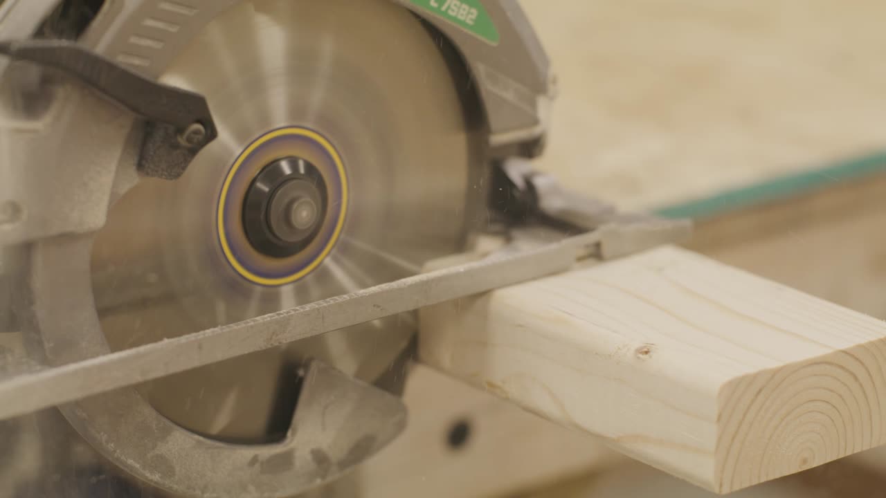 Circular saw cutting a piece of wood close up with slow motion video.