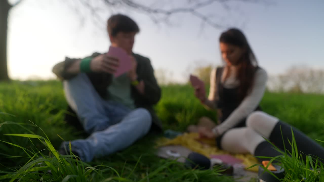 Young Adults Playing Cards Outdoors