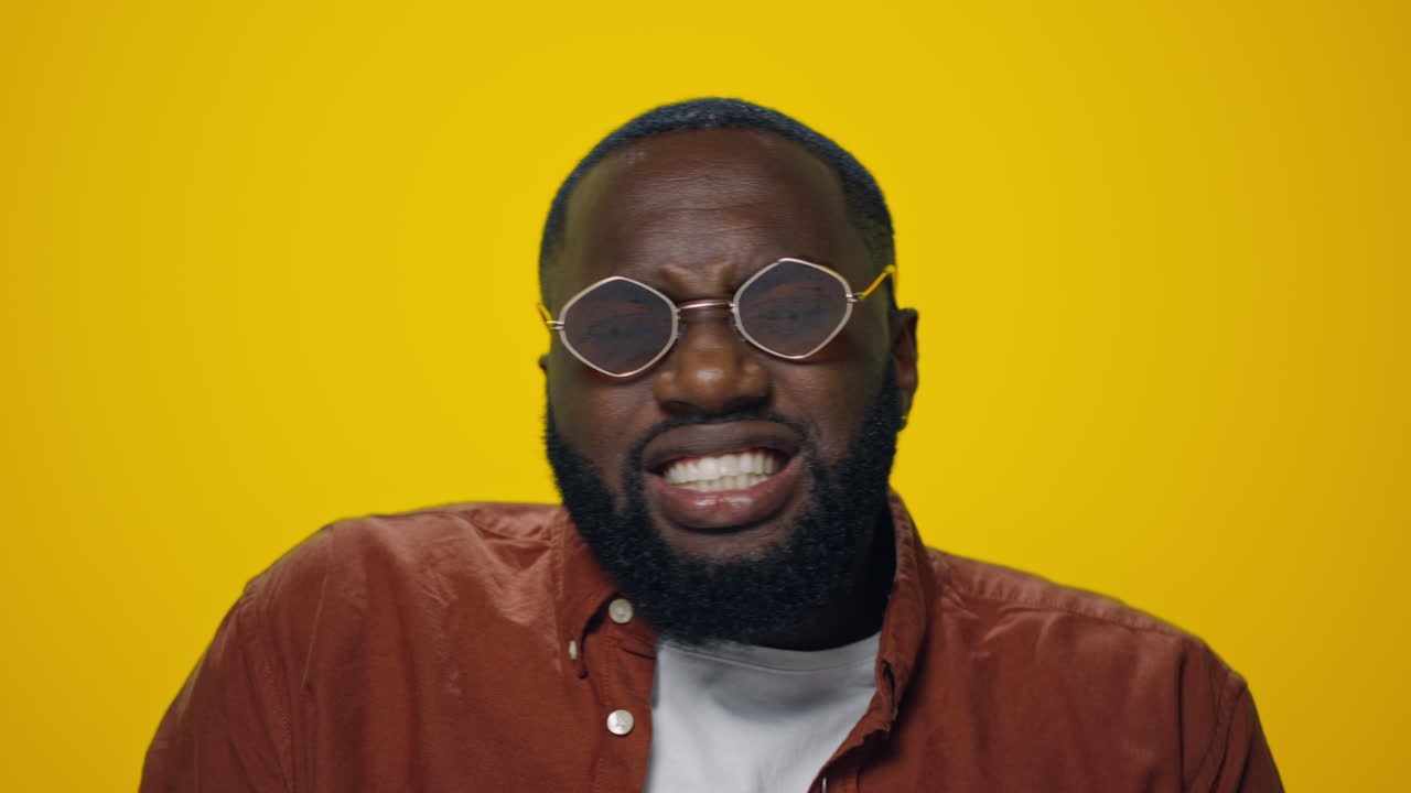Portrait of bearded african american man dancing on yellow background.