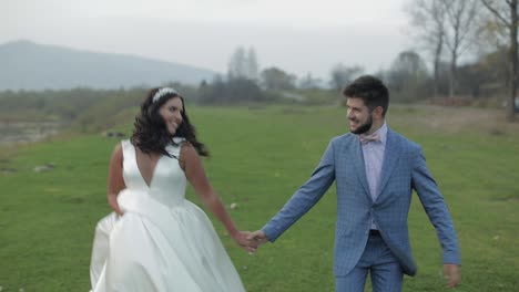 Wedding-couple-running-near-mountain-river.-Groom-and-bride-in-love