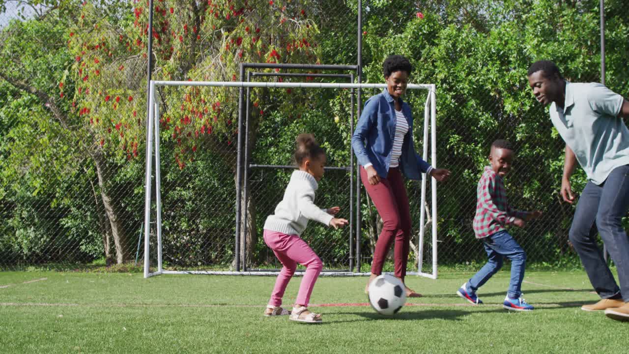 feliz familia afroamericana jugando al fútbol en el parque
