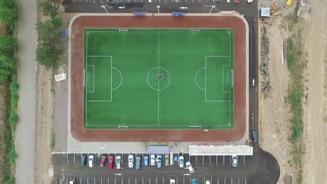 Top-down-aerial-view-of-people-on-football-or-soccer-field,-drone-zoom-in