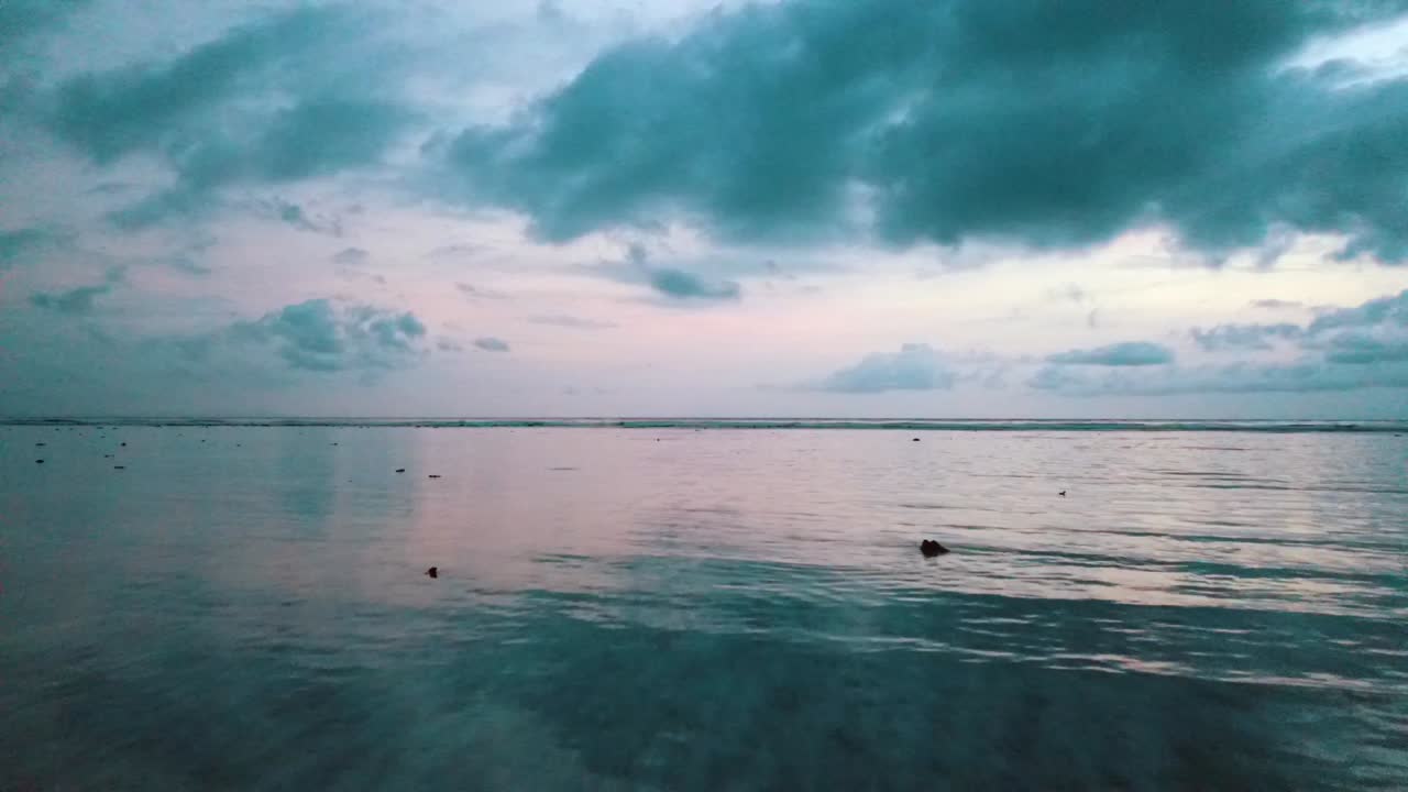 100만 달러의 항공 비행은 극적인 구름 하늘 길리 트라왕안 발리 롬복 일몰 후 푸른 시간에 작은 섬 필립 마니츠와 함께 빈 외로운 해변의 드론 샷을 천천히 상승