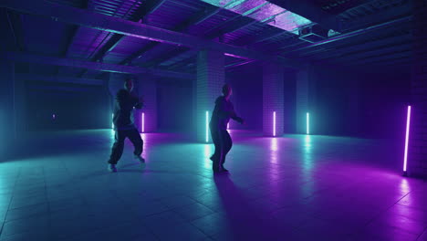 professional hip hop break dancers . stylish young couple dancing with real strobe lights . against blue background of led lights. dancing young couple in colourful neon studio light hip hop dancers