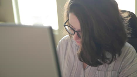 a caucasian woman's face working at a desk in slow motion