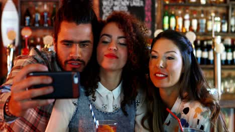 amigos tomando selfies en el teléfono móvil mientras toman un cóctel