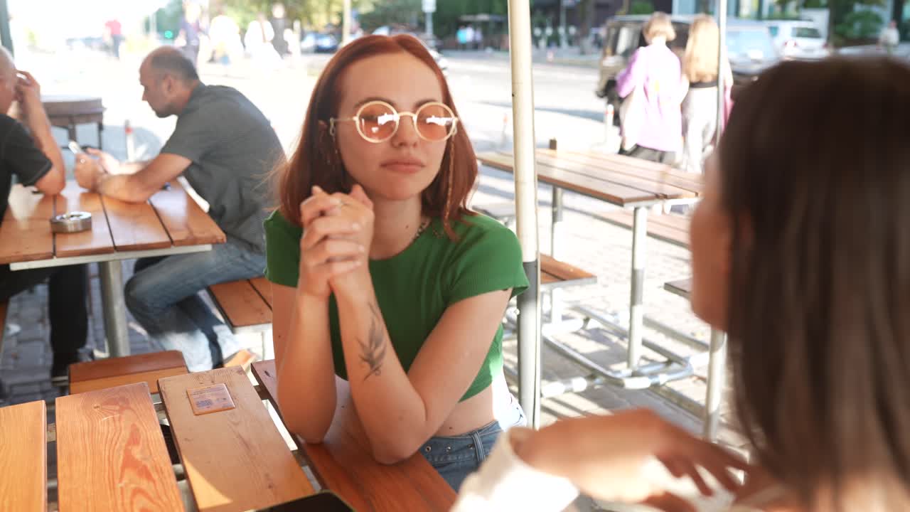 두 여자 가 야외 카페 에서 대화 하고 있다