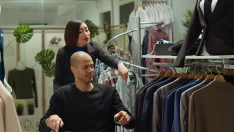 man in wheelchair shopping for clothes with assistance