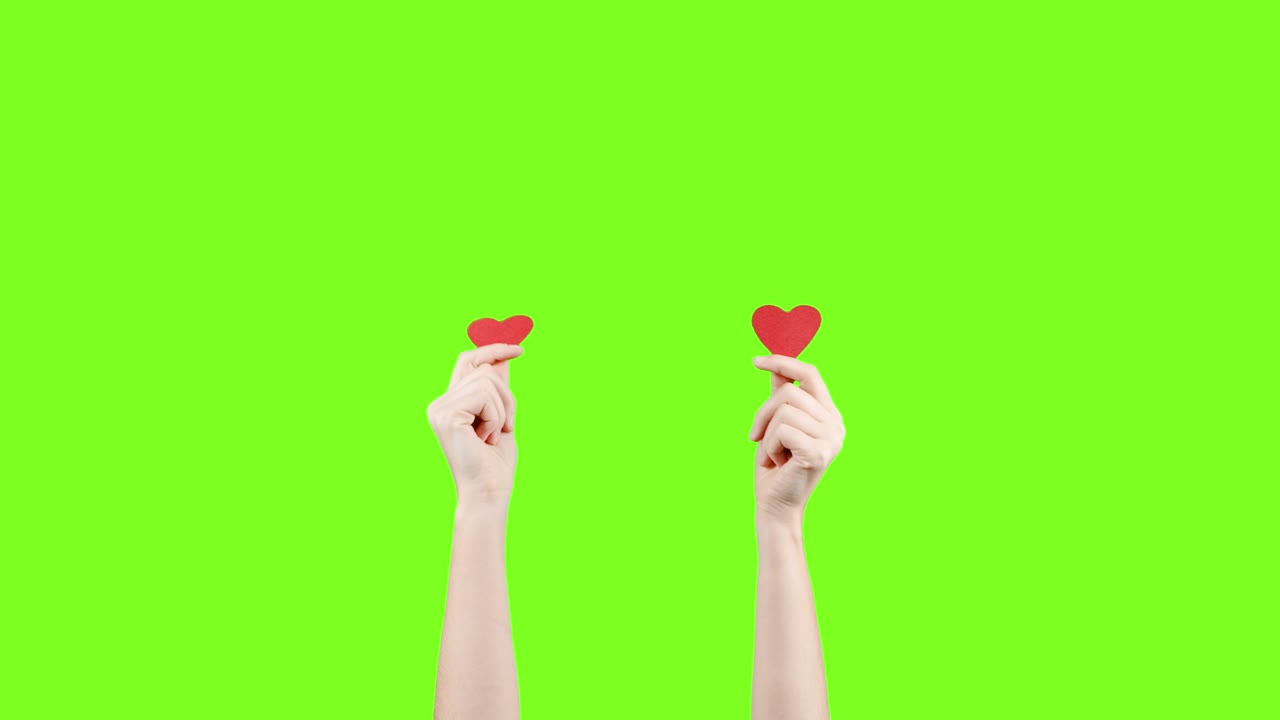 여성 블로거는 녹색 화면에서 작은 빨간 심장을 손에 들고 있습니다. 소셜 네트워크에서와 같이. 발렌타인 데이, 국제 여성의 날, 사랑