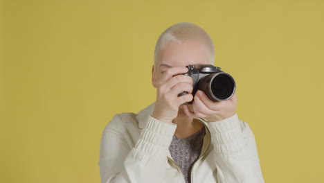 кавказская модель позирует с фотоаппаратом на фоне желтого фона 02