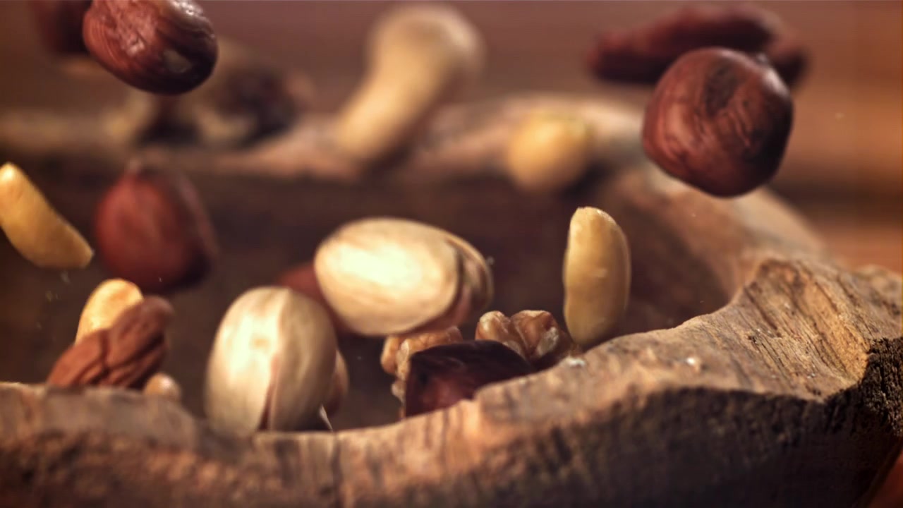 Assorted Nuts Falling into a Rustic Wooden Bowl in Slow Motion