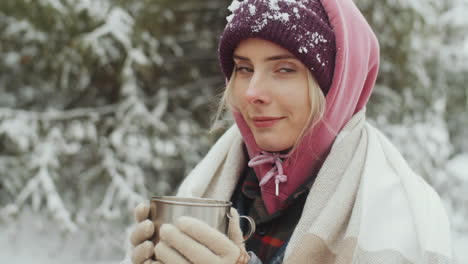 portrait of beautiful woman with metal mug in winter forest