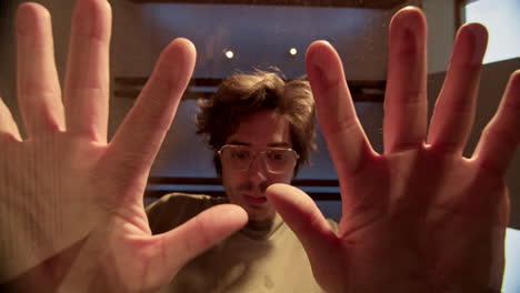 man with hands pressed against a glass surface