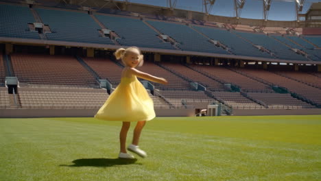 a young girl running across an empty sports stadium field
