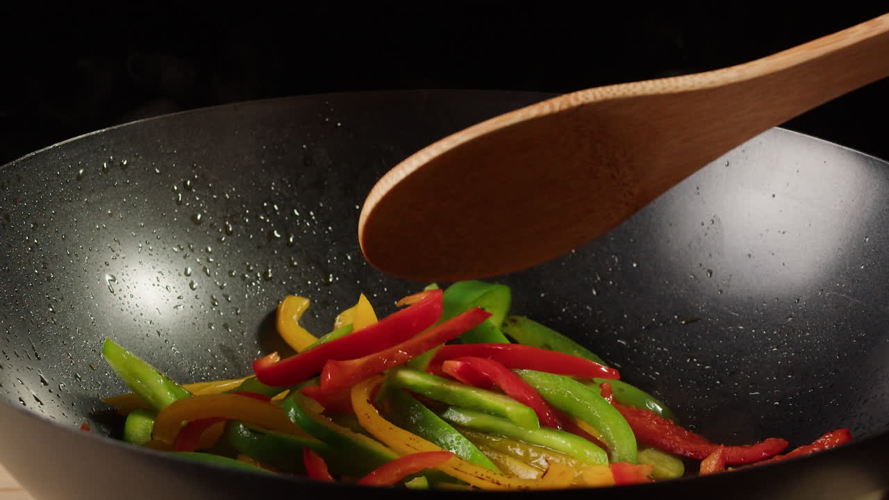 Stir-frying colorful bell peppers in a wok