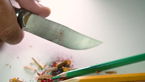 Footage-of-hands-slowly-sharpening-a-pencil-and-some-coloured-pencils-with-a-sharp-knife