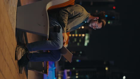 man working on laptop outdoors at night in city
