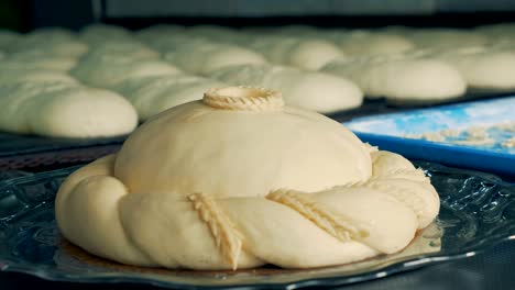 baker decorating a round loaf with pieces of dough turning the plate around, close up