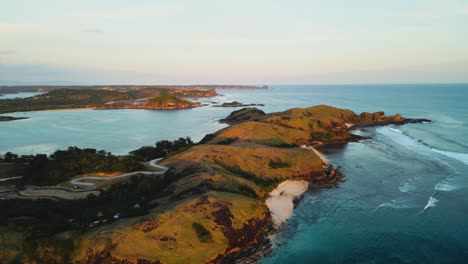 aerial orbiting shot over lombok island with famous bukit merese hills and sandy beaches with crashing waves from the ocean. lombok,indonesia.