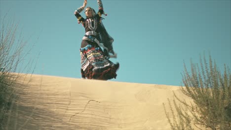 Gypsy-woman-smiling-and-dancing-on-a-desert-sand-dune