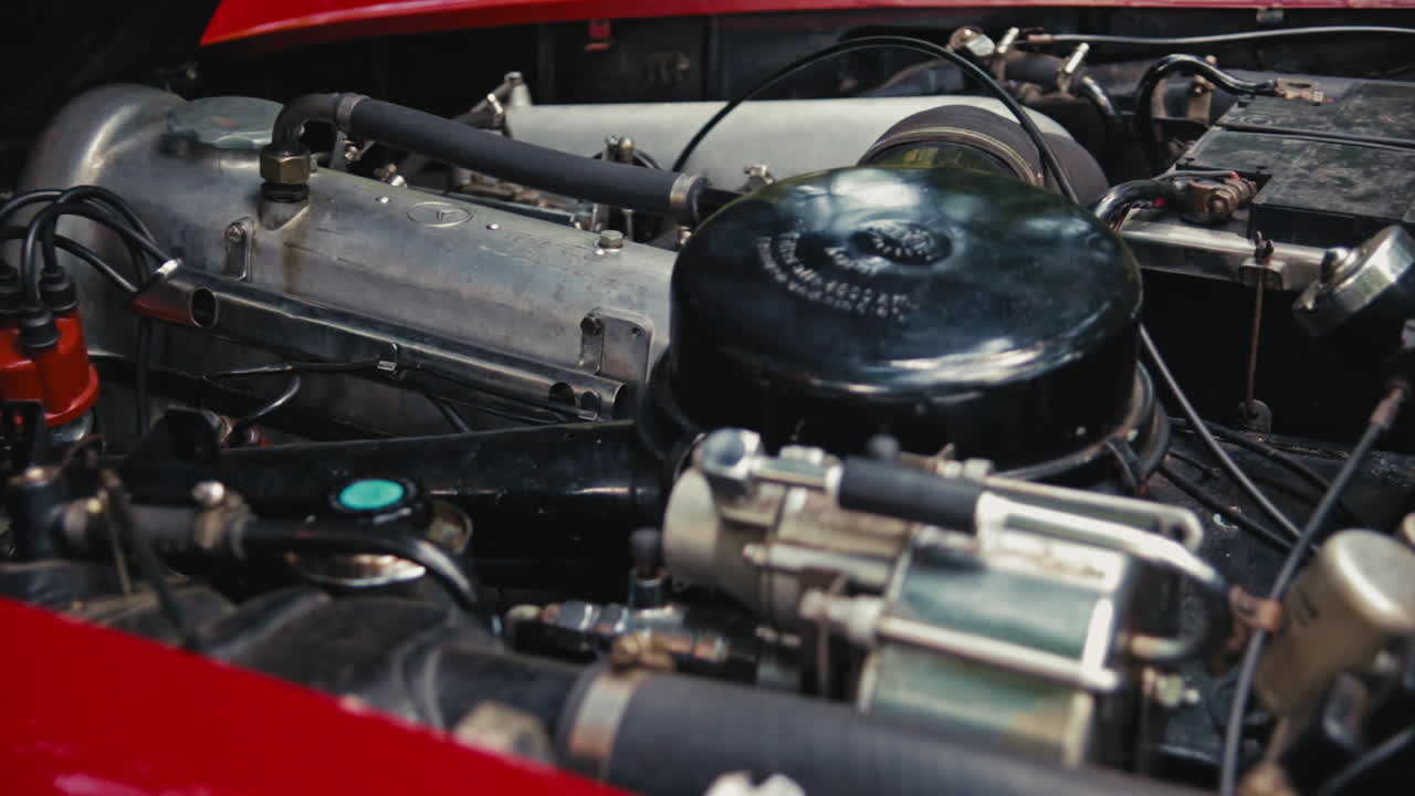 Start of a red Old-Timer car. Close shot of a old engine starting. Red Mercedes SL cabriolet in the woods on a sunny day.