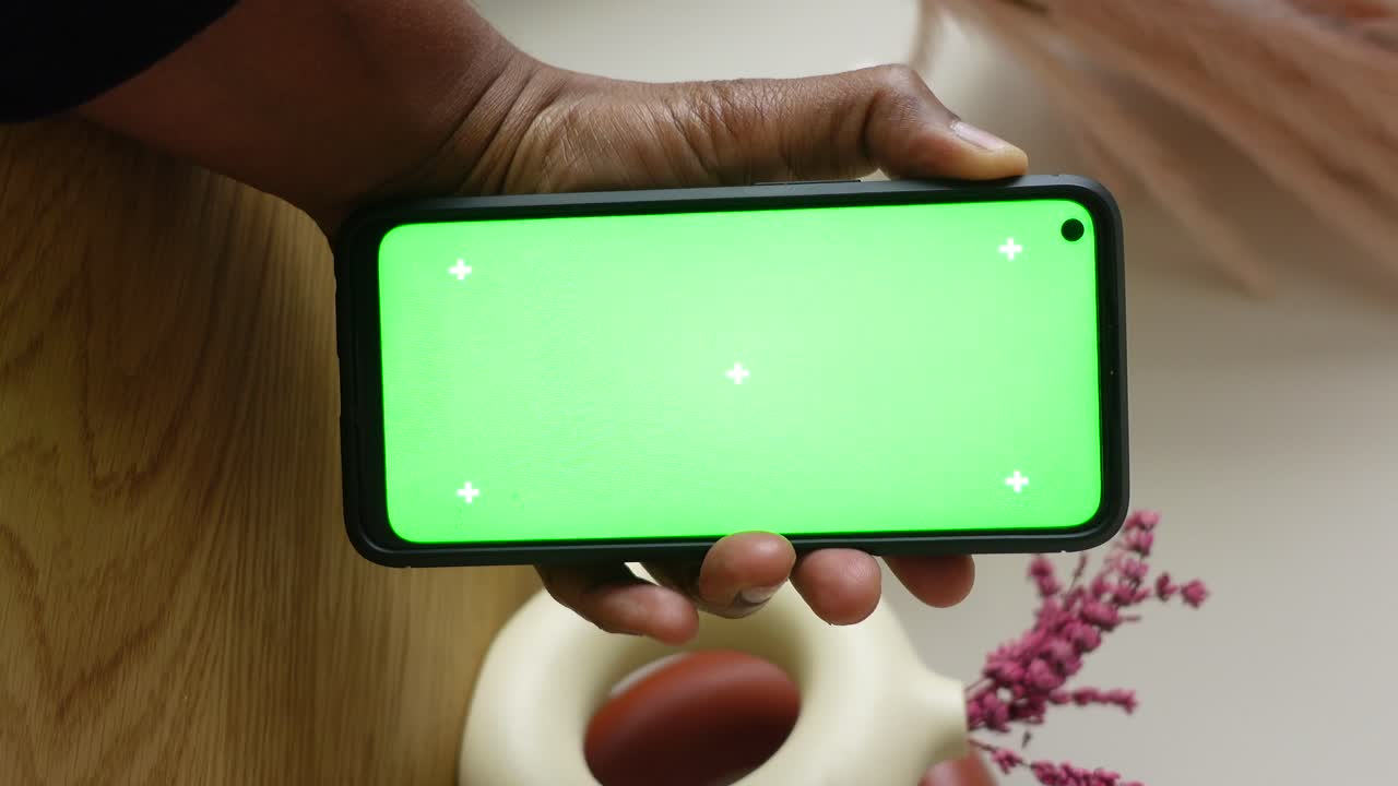 mano sosteniendo un teléfono inteligente con una pantalla verde