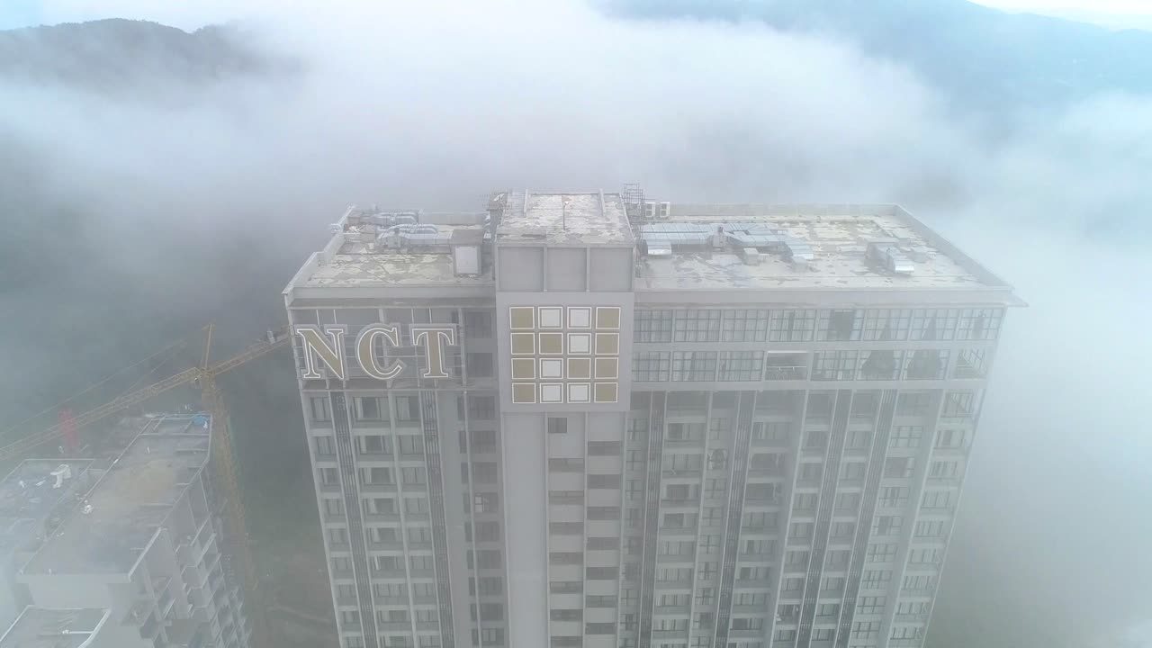 Aerial descending shot of the Grand ION Delemen hotel in Genting Highlands covered in fog.
