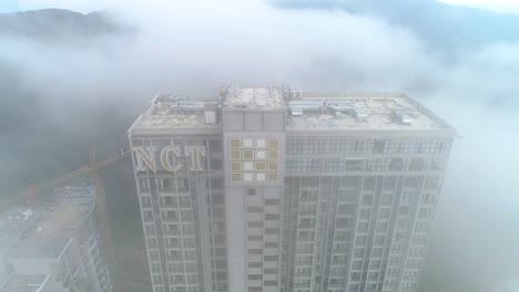 aerial descending shot of the grand ion delemen hotel in genting highlands covered in fog.