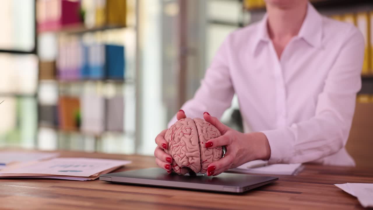 Woman holding a brain model on a desk