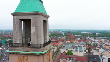 Pull-back-shot-of-Rathaus-Spandau-tower-with-tower-clocks.-Aerial-view-of-old-town-and-busy-multilane-road.-Berlin,-Germany