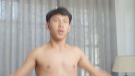 집에서 셔츠를 벗고 운동하는 동안 박수와 함께 점프 잭을 하는 아시아 십대 소년의 클로즈업