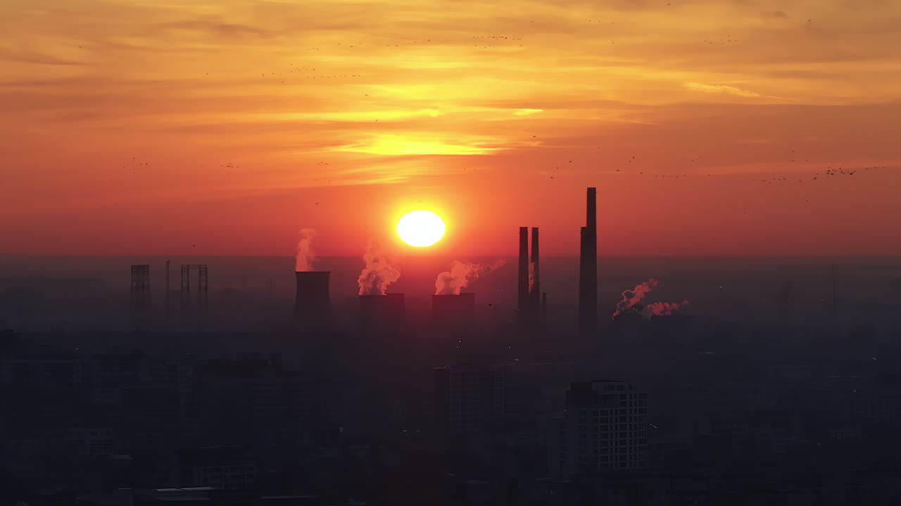Aerial drone view of thermal power stations in Bucharest at sunset, red sun. Flying birds. Romania