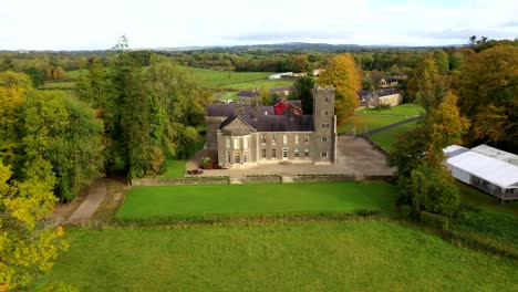 aerial tracking left reveal of castle grounds with vibrant fall foliage and winding driveway in golden sunlight, belle isle castle