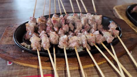 Fresh-goat-satay-on-hotplate-being-cooked,-close-up-orbit-view