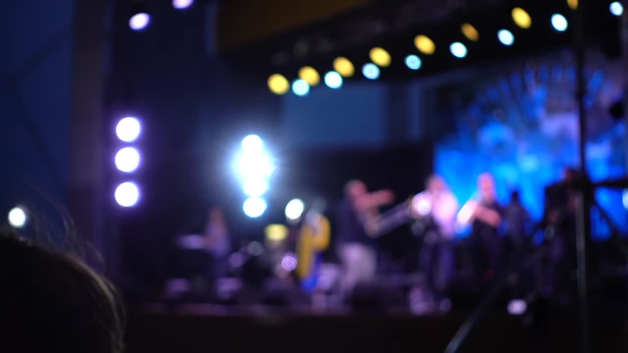 Concerto sul palco. Folla di persone e musicisti sulla scena. Fuori fuoco