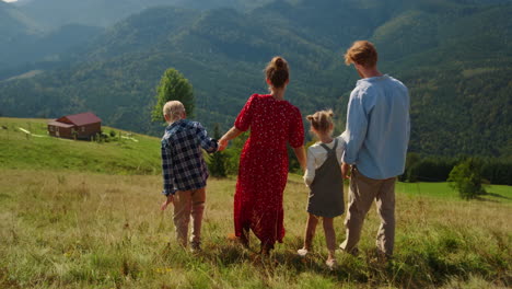 familie kommt den hügel hinunter und genießt den sommer. paar spazieren mit kindern in der natur.