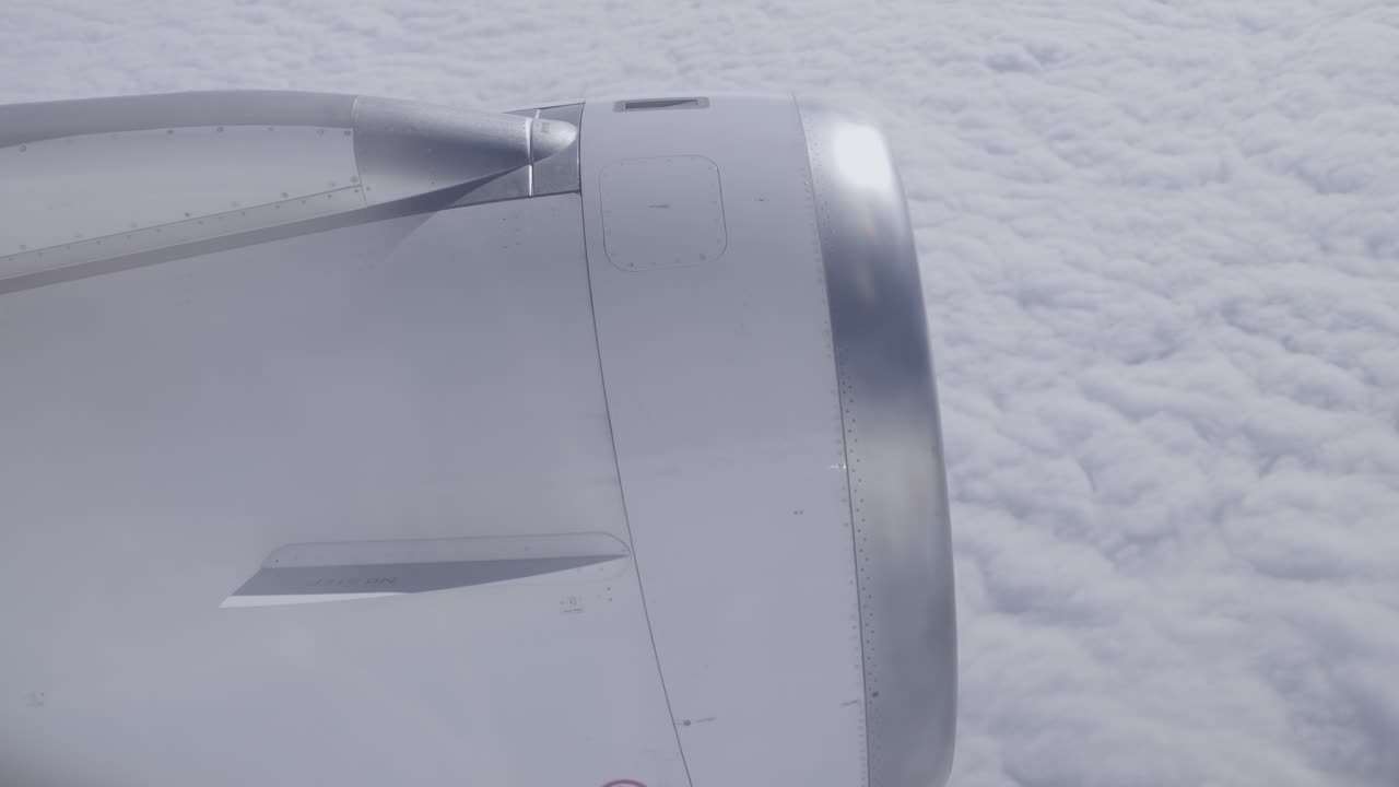 View of airplane engine from passenger window flying above thick cloud layer