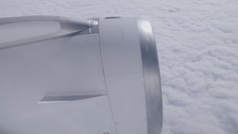view of airplane engine from passenger window flying above thick cloud layer