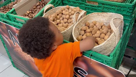 niño africano de dos años contando nueces en un supermercado