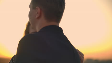 two lovers embracing dancing on top of a skyscraper overlooking the city at sunrise sunset. romantic setting