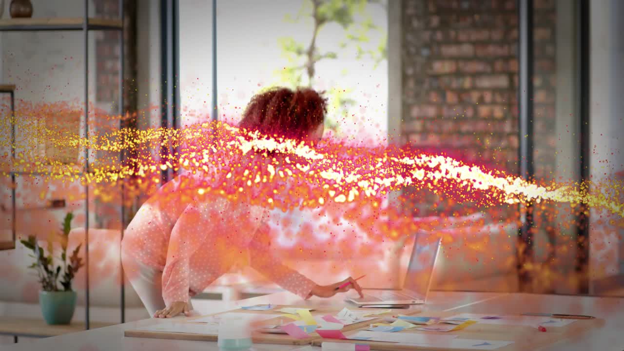 Designer holding pink card planning sorting notes using laptop as particle ribbon sweeping torso