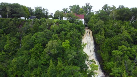 mailloux waterfall gushing on cliff on saint lawrence river in beaumont, quebec - aerial