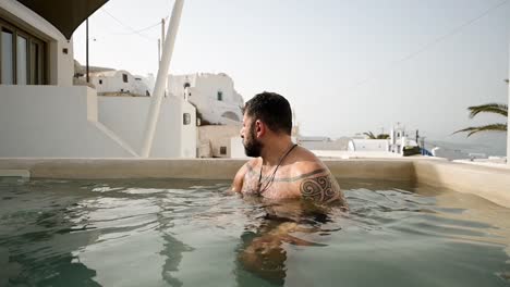 Mann-Im-Typischen-Santorini-Pool-Mit-Blick-Auf-Die-Caldera