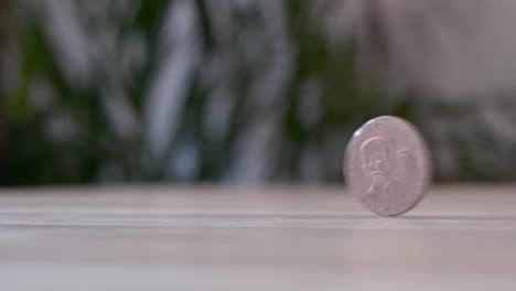 Macro-closeup-of-coin-flipping-on-table,-50-cent-Ecuador-dollar,-slow-motion