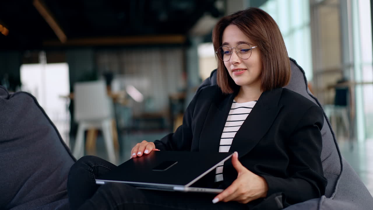 Freelancing lady working in the comfortable place on her laptop. Woman finishes her workday, closes laptop and leans in the chair relaxed.